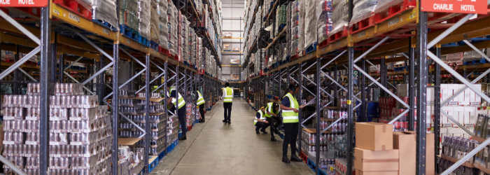 Large warehouse with stock stored on the shelves, people in high vis jackets working