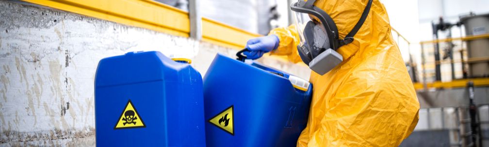 Chemical Supplier Challenges A person in yellow overalls and a face mask moves a blue container with a toxic skull and crossbone warning on the side