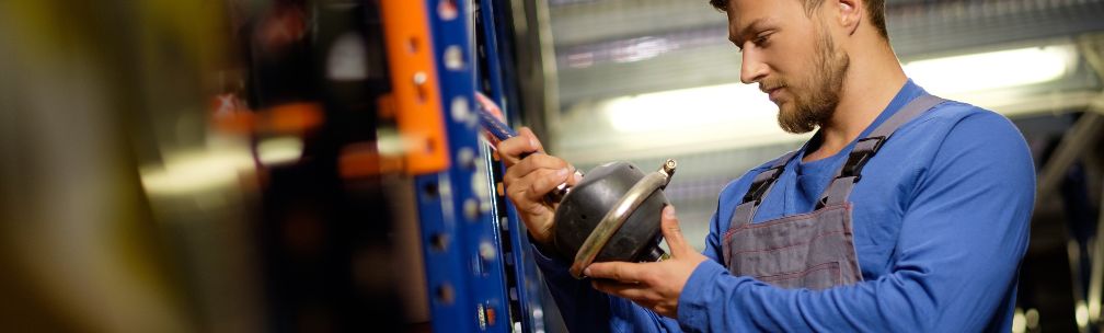 A person inspects a car part in a warehouse