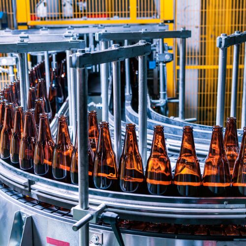 Empty glass bottles on a factory assembly line conveyor belt ready to be filled
