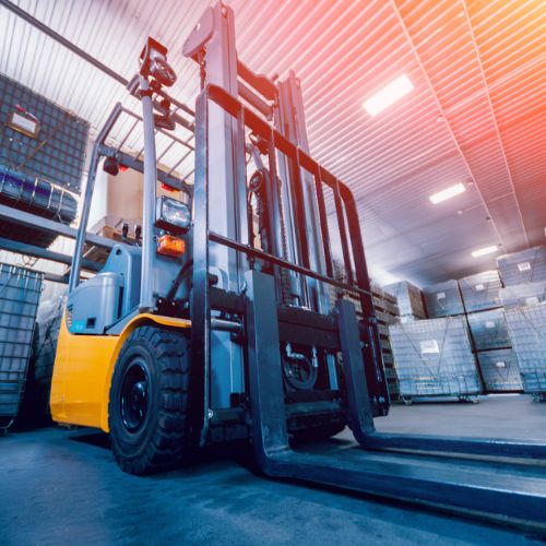 An image of a forklift truck surrounded by stock in cages within a warehouse