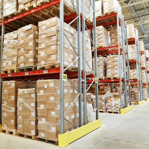 Cardboard boxes containing stock, stored on bays of industrial racking in a warehouse