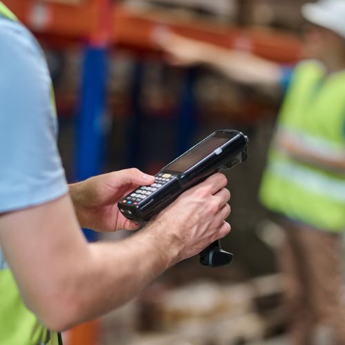 Someone operating a handheld barcode scanner in a warehouse