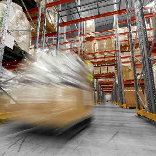 An image of a forklift truck surrounded by stock in cages within a warehouse