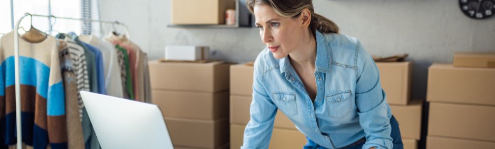 Person leaning over a computer with cardboard boxes behind them