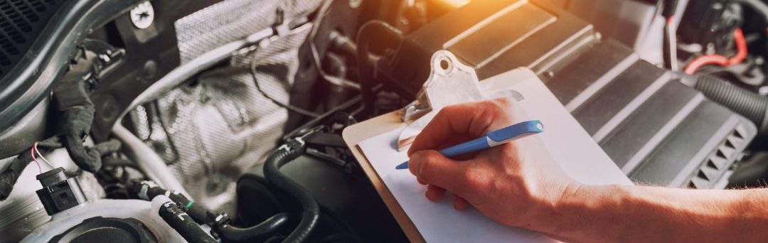 Close up of someone taking notes inside a car's engine bay