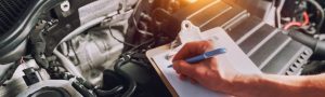 Close up of someone taking notes inside a car's engine bay